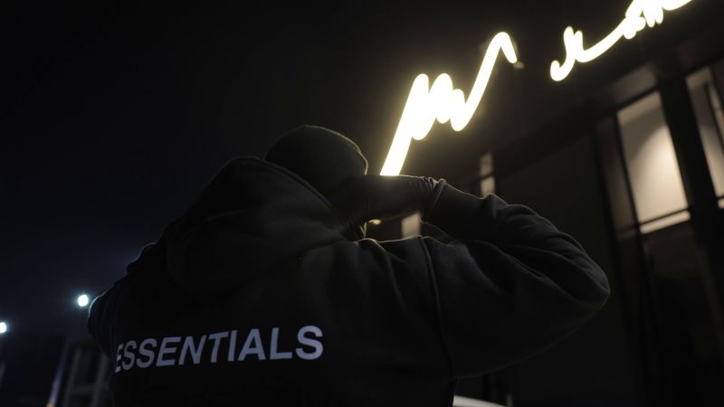 The thief in a wool balaclava under the showroom sign