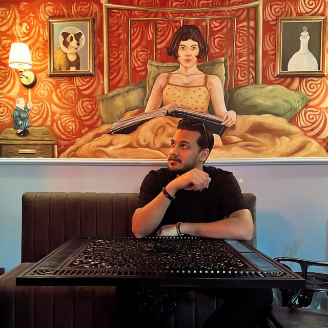Mohammed at Amélie Galata, under a mural of Amélie